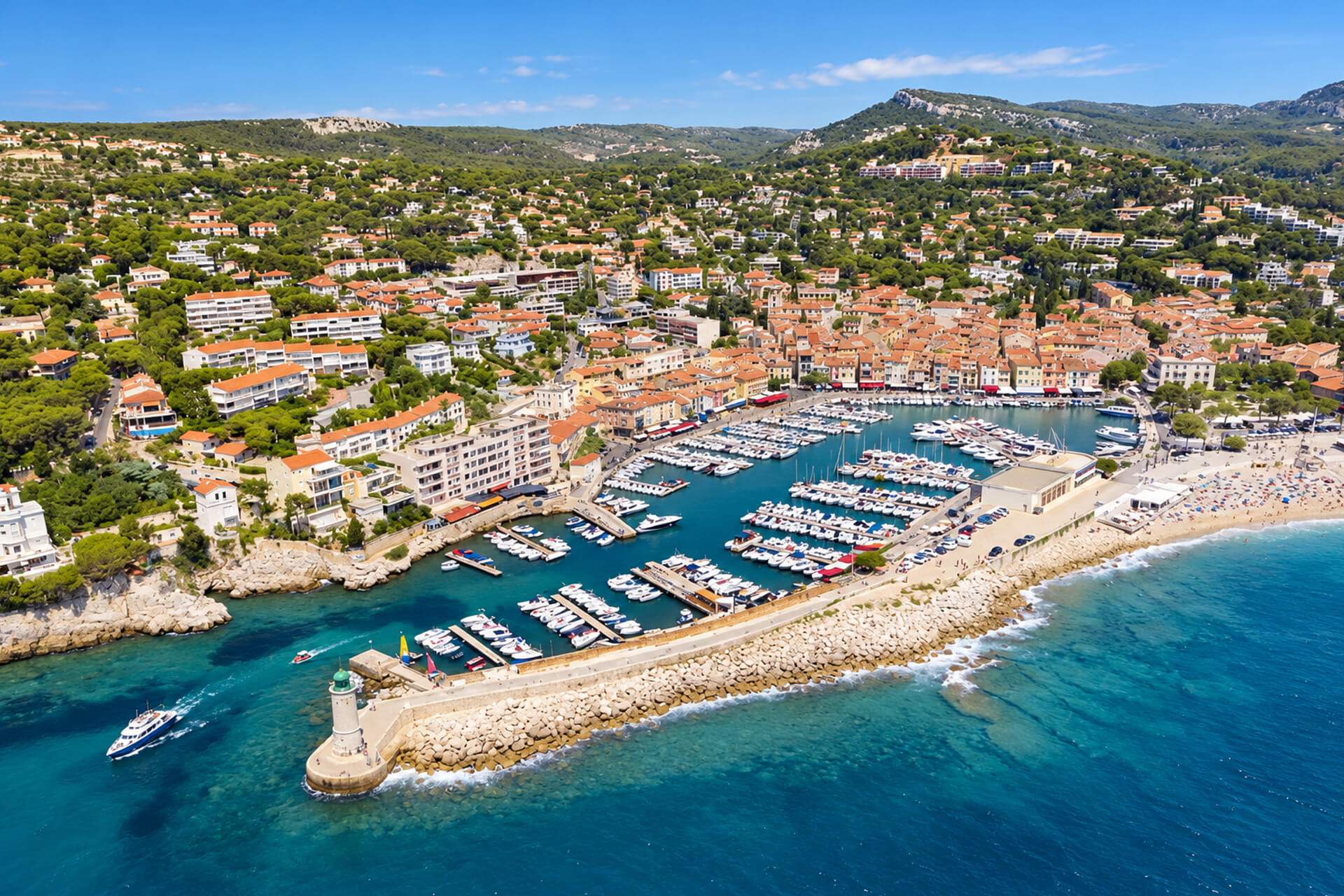 Vue aérienne du port de Cassis, de sa digue et de son phare, la ville au pied des collines