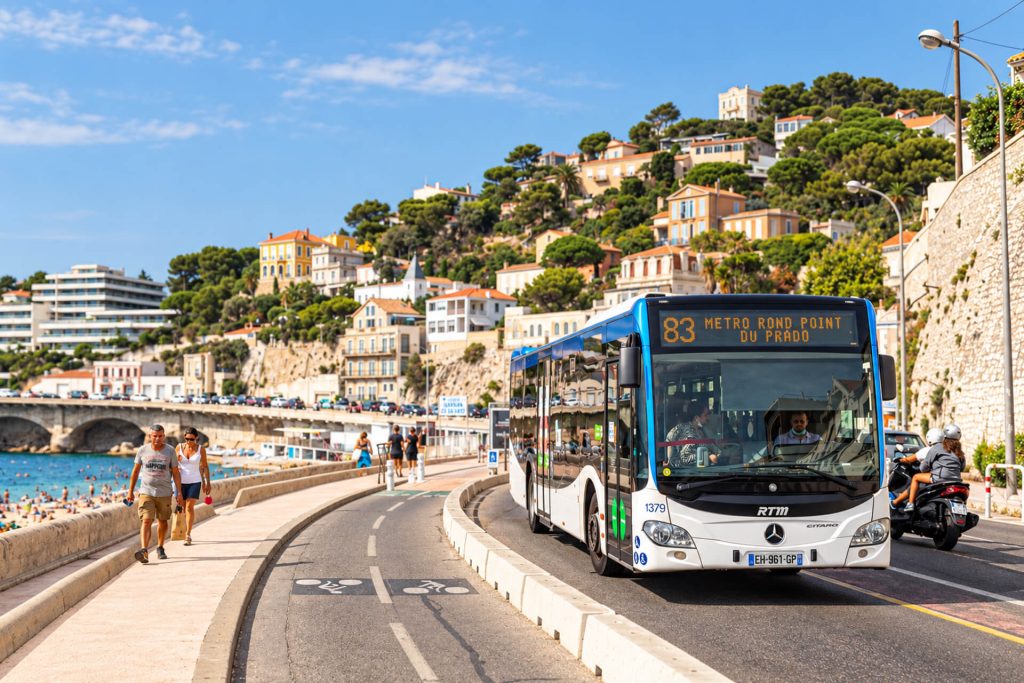 Bus RTM de la ligne 83 sur la corniche Kennedy, piétons sur le trottoir au bord de la mer