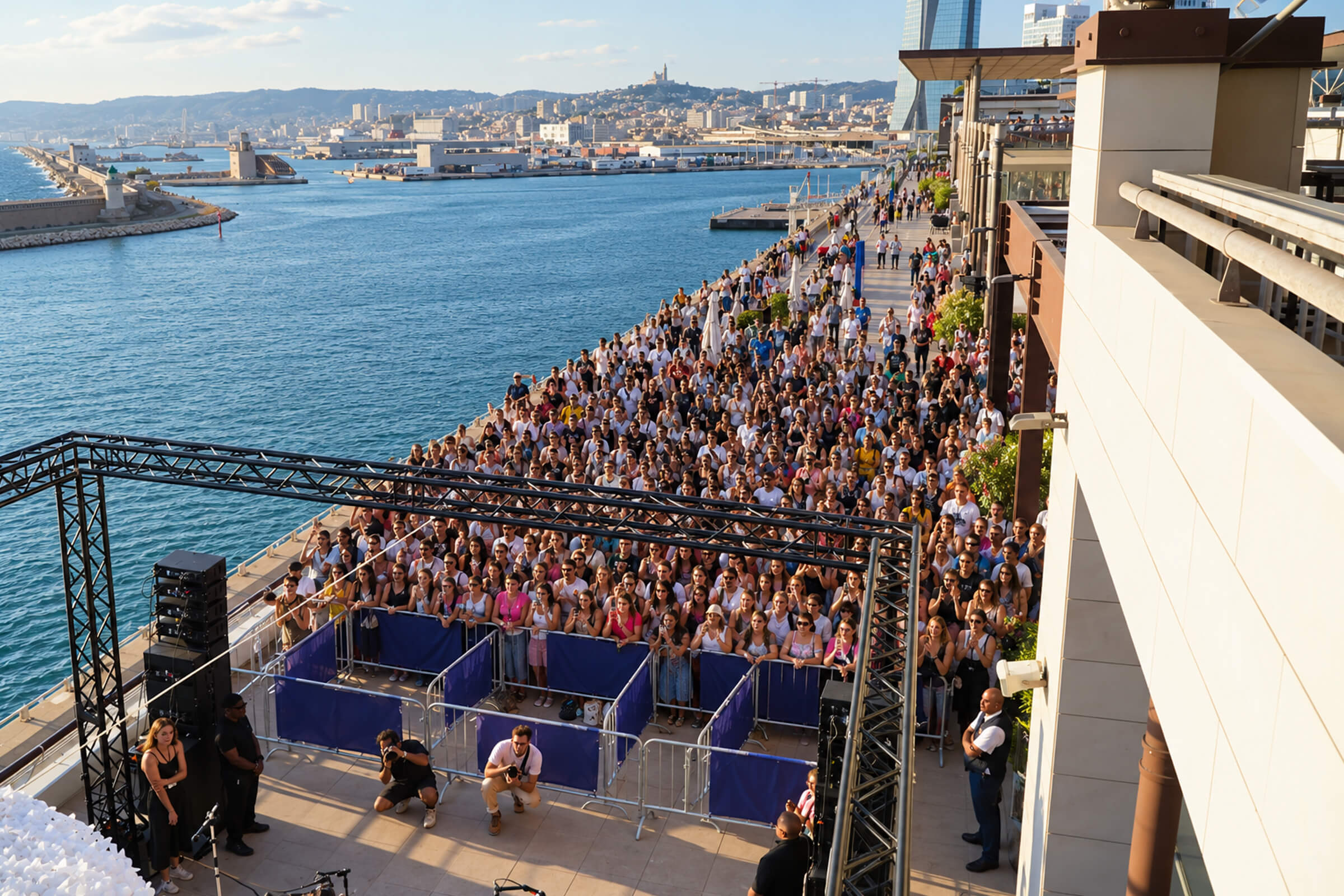 Concert en plein air sur les quais du port, foule face à la mer et Notre-Dame de la Garde au loin