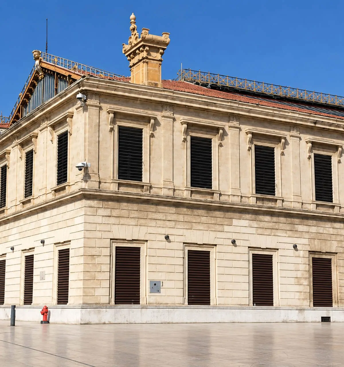 Façade en pierre de la gare Saint-Charles et sa grande verrière, parvis ensoleillé