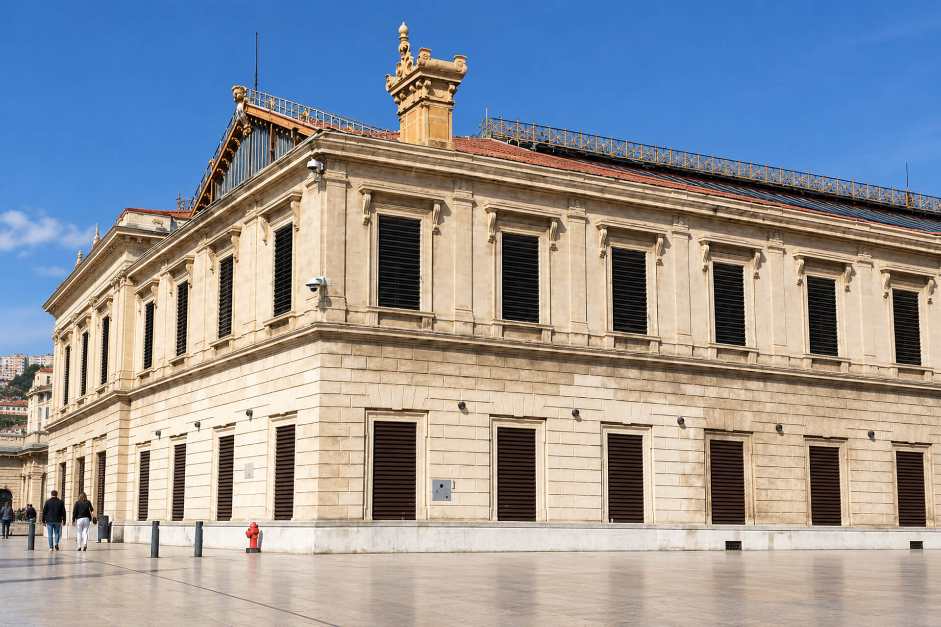 Façade en pierre de la gare Saint-Charles et sa grande verrière, parvis ensoleillé