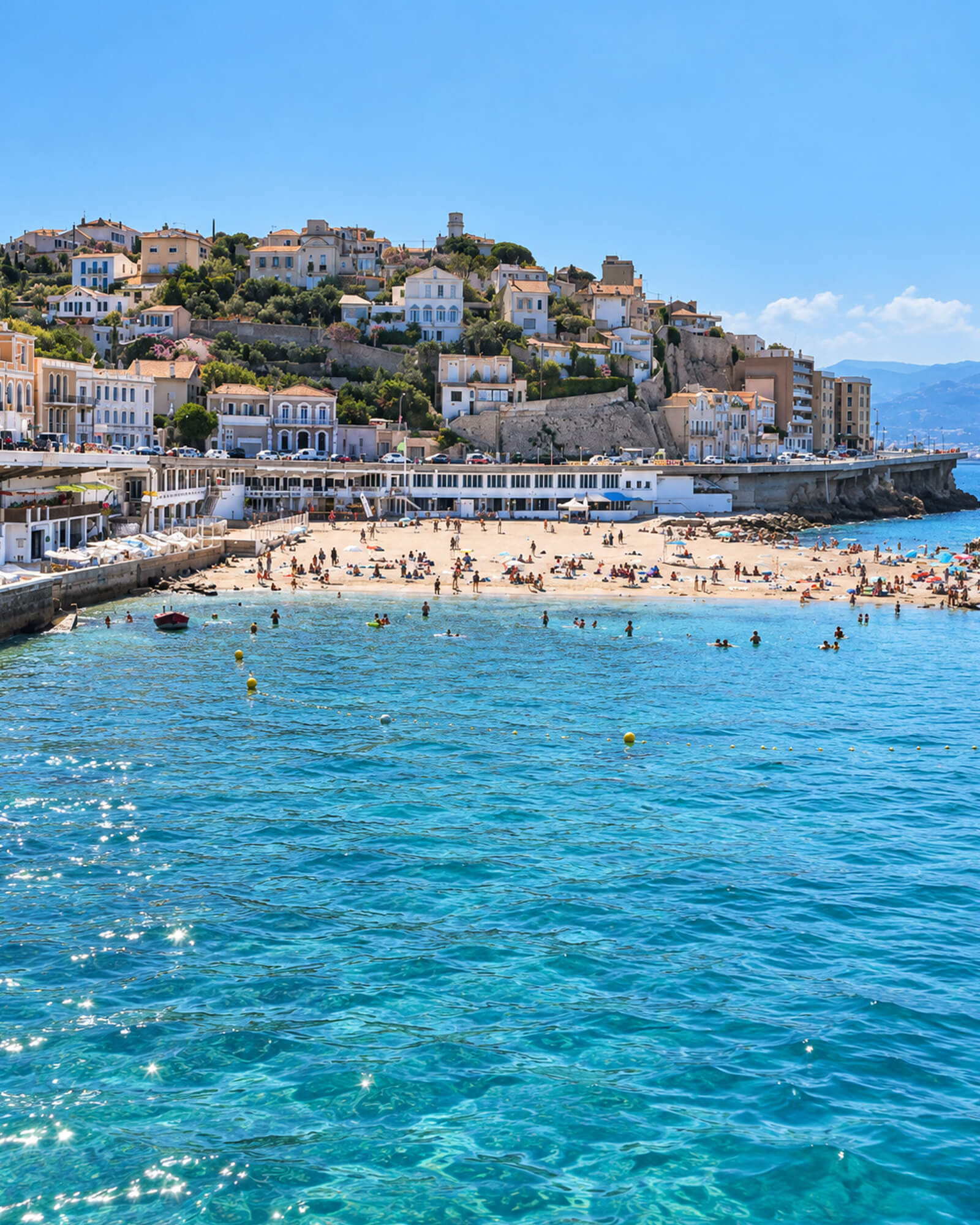 Plage de sable de Marseille vue depuis la mer turquoise, avec la ville en arrière-plan