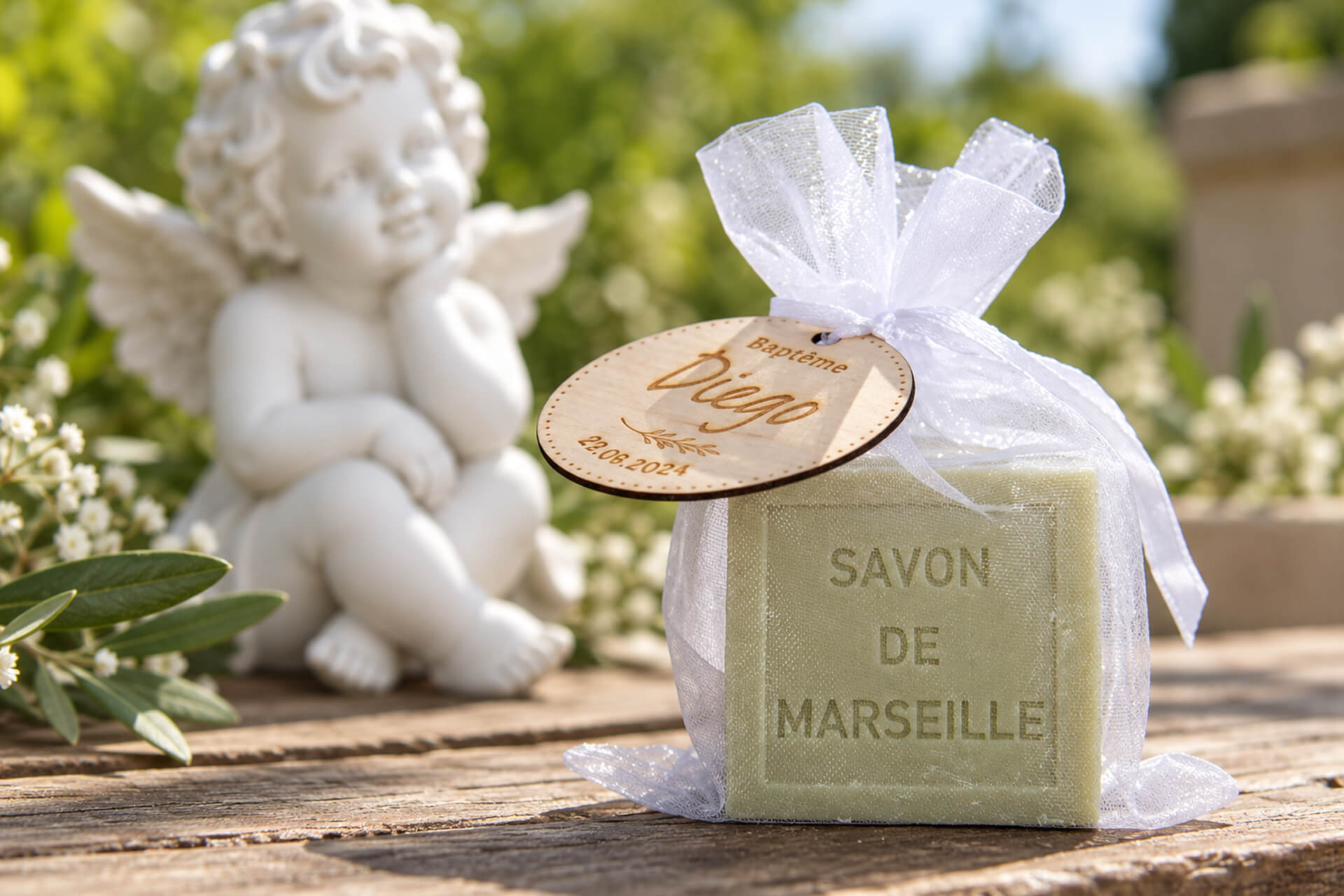 Cube de savon de Marseille emballé dans un sachet en organza, statue d’angelot en arrière-plan