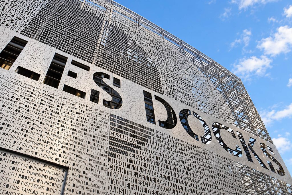 Enseigne « Les Docks » en métal ajouré sur la façade, vue en contre-plongée