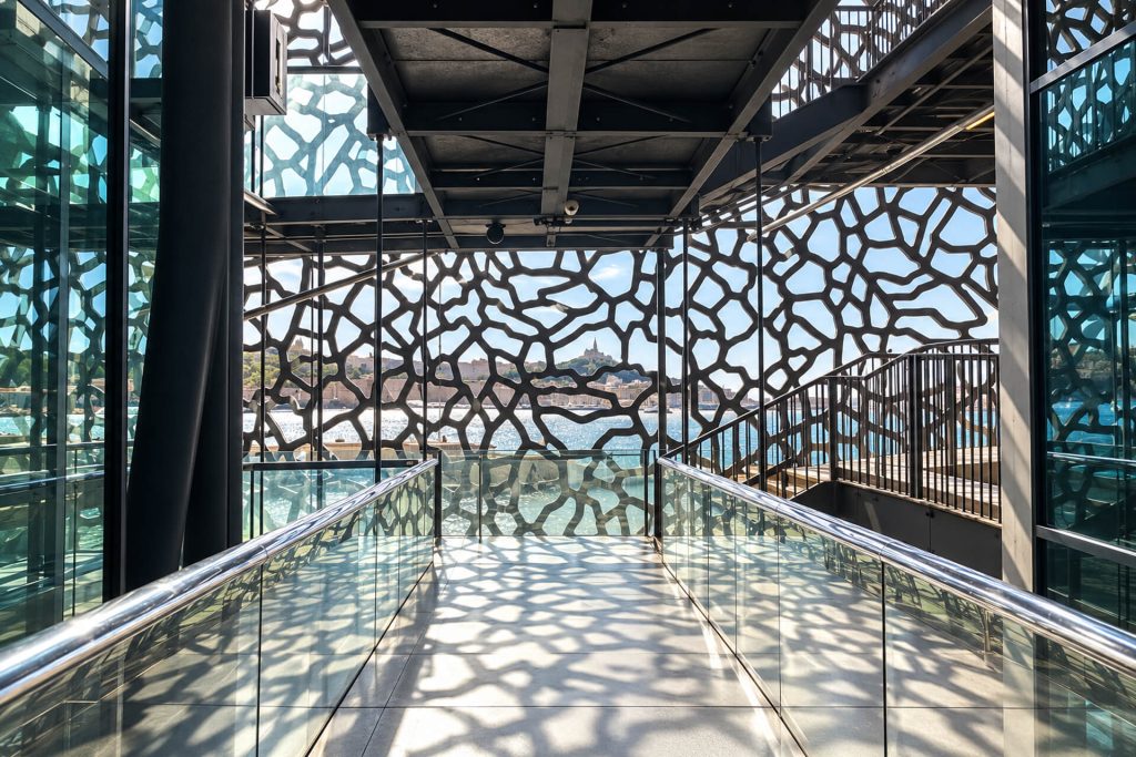 Passerelle intérieure du Mucem et ombres de sa résille de béton sur le sol