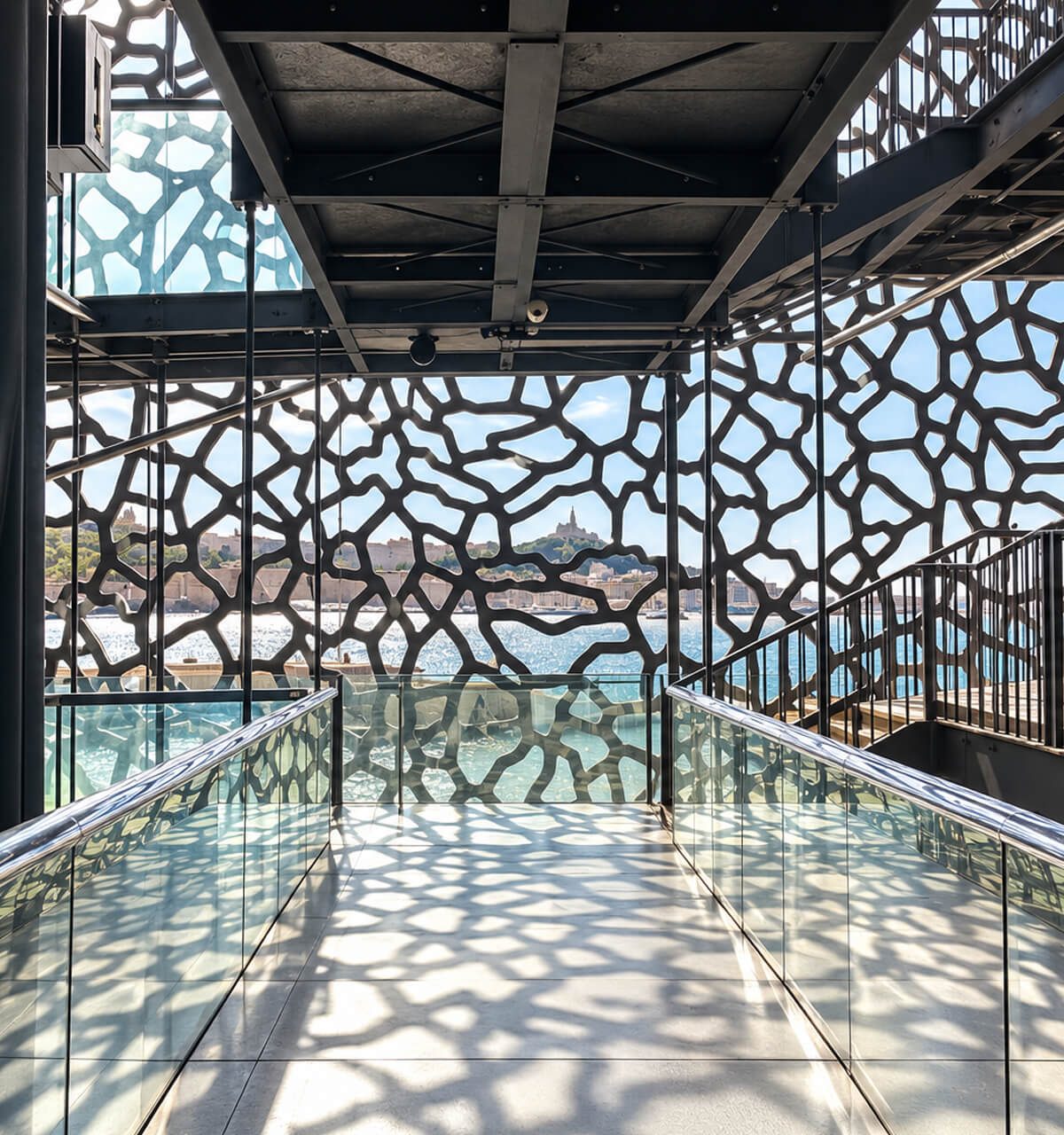 Passerelle intérieure du Mucem et ombres de sa résille de béton sur le sol